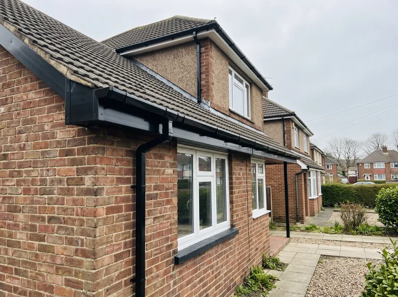 Newly replaced black uPVC guttering and fascia boards on a house